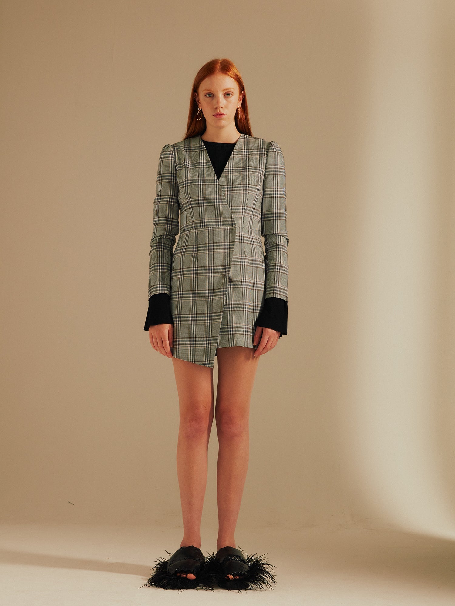 model stands wearing the Amelia Heritage Asymmetric Blazer Dress with fluffy slippers