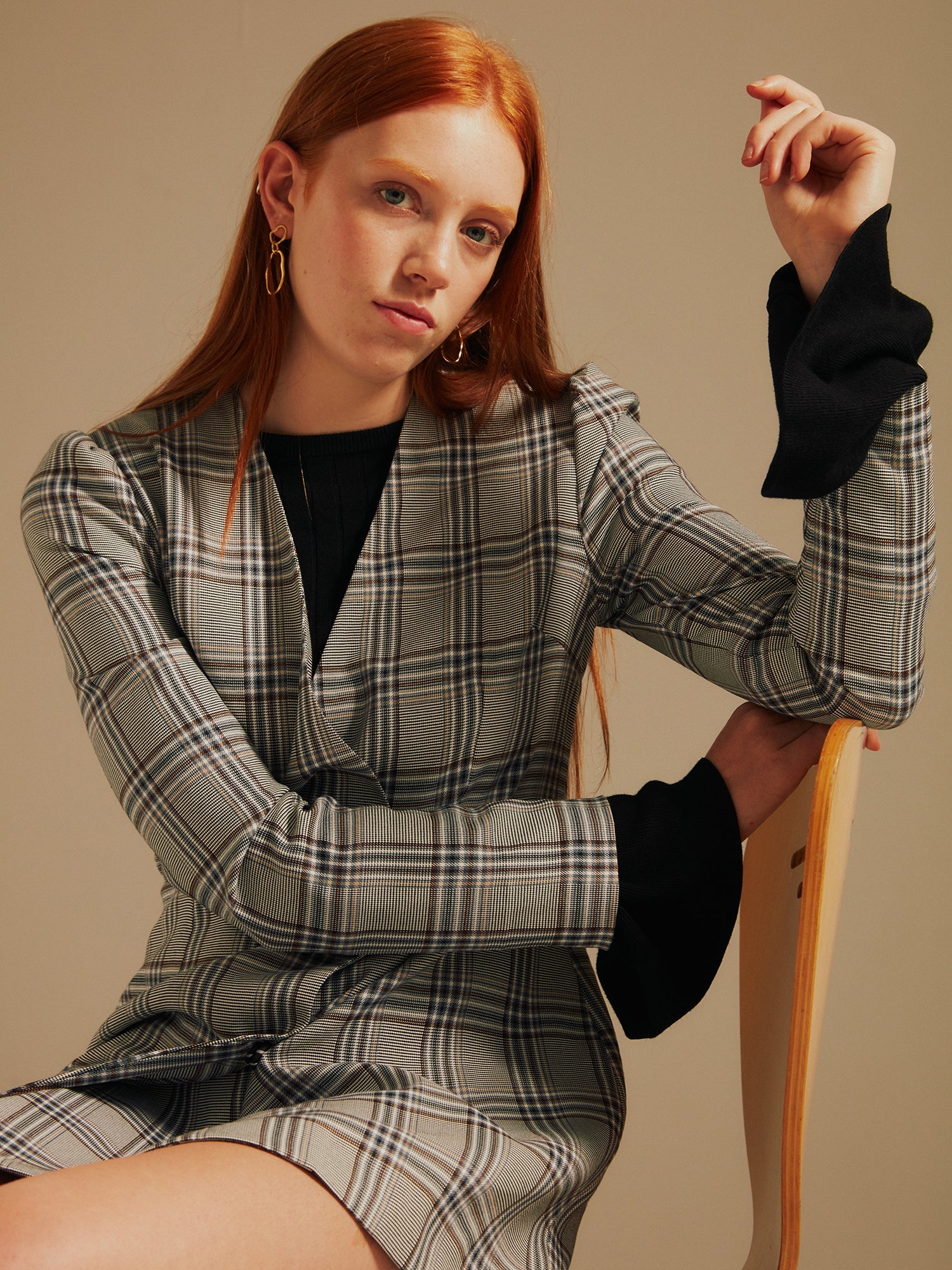 cropped image of the model sat in a chair in the Amelia Heritage Asymmetric Blazer Dress with her arm leaning on the back