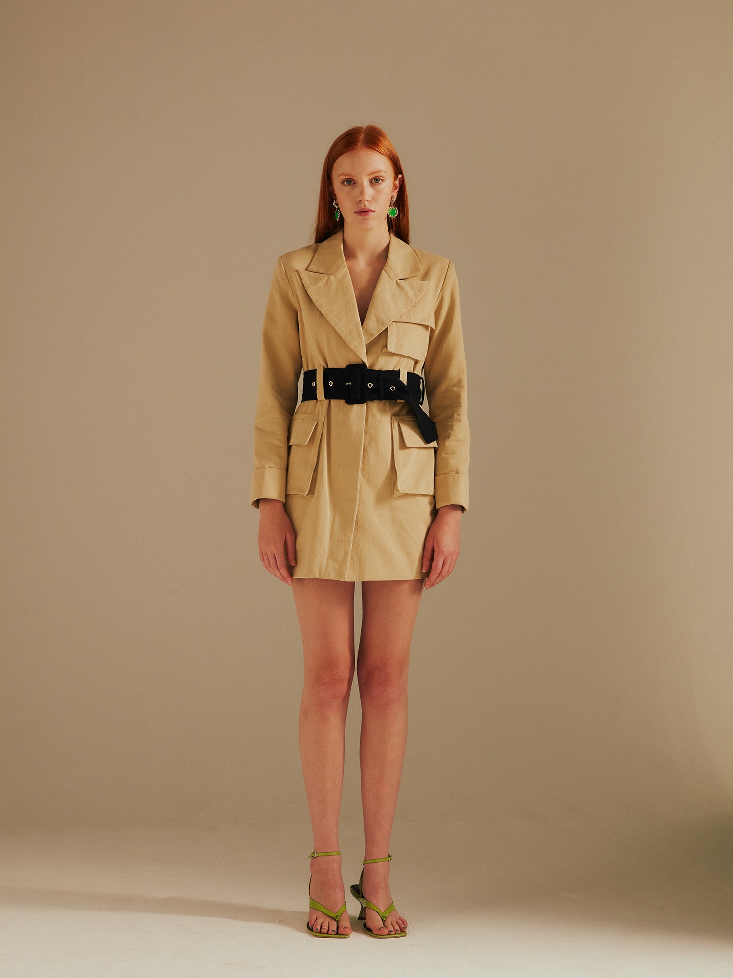 model wears the Ashley Utility Belted Blazer Dress standing facing the camera with green strappy sandals