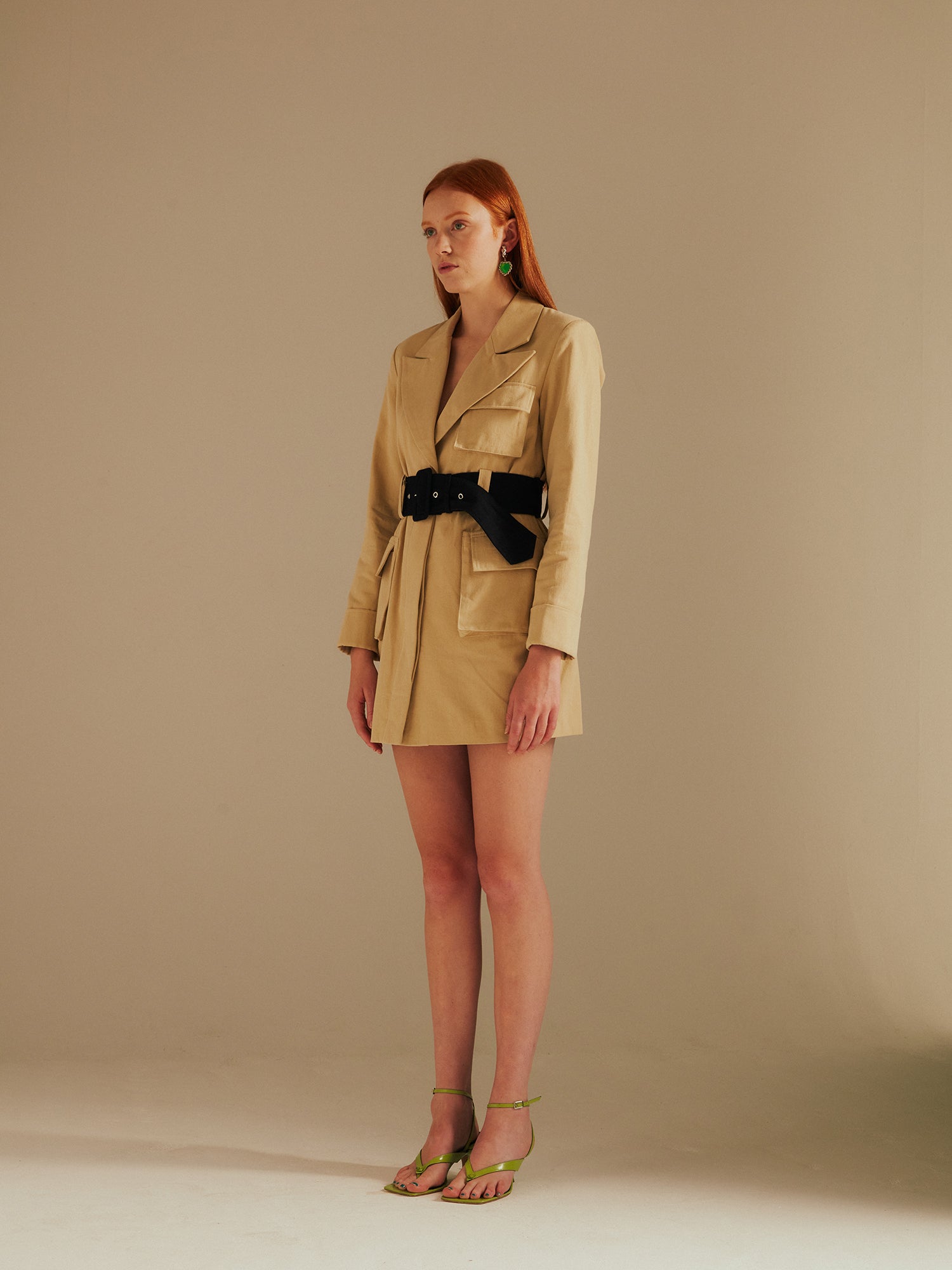 model stands up straight in the Ashley Utility Belted Blazer Dress with green strappy sandals