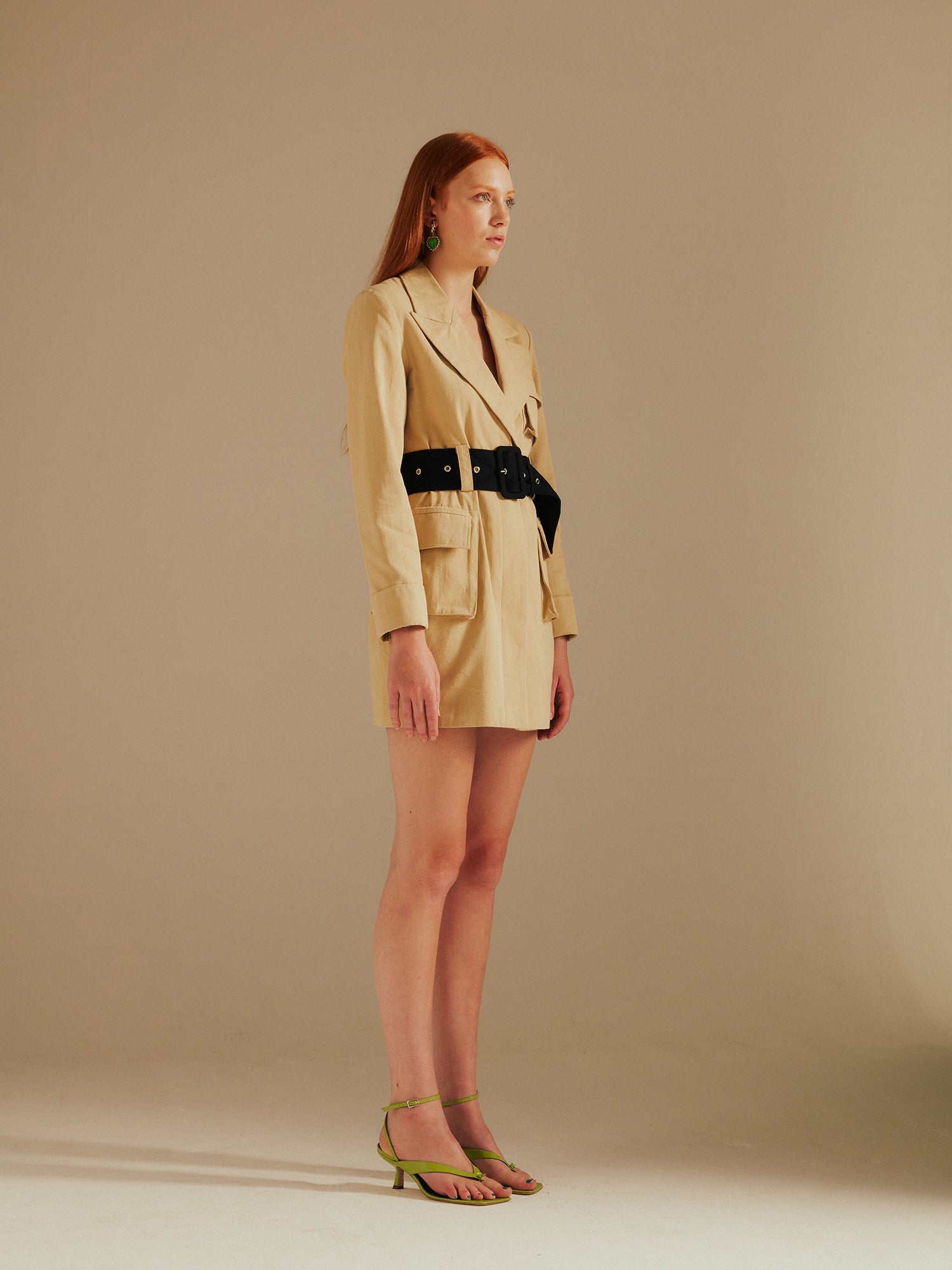 model faces away from the camera in the Ashley Utility Belted Blazer Dress with green sandals in a studio